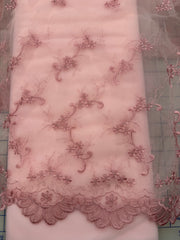 Pink floral lace fabric with embroidered vines and a scalloped hem, shown laid flat on both Rosette tulle and a gridded cutting mat.